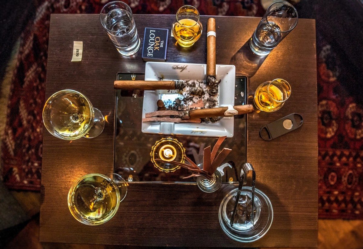Cigars resting in a Davidoff ashtray beside whisky glasses